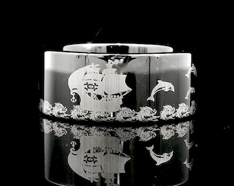 May include: A black tungsten ring with an engraved design of a ship sailing on waves with dolphins jumping in the water.