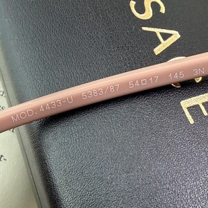 May include: Close-up of a light pink eyeglass arm with the text "MOD. 4433-U 5383/87 54 17 145 3N" printed in white. The arm is resting on a dark surface.