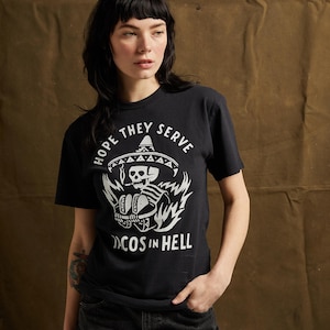 Peut inclure: T-shirt noir avec un graphique blanc d'un squelette portant un sombrero et tenant des tacos. Le texte "Hope they serve tacos in hell" est imprim&eacute; sous le graphique.