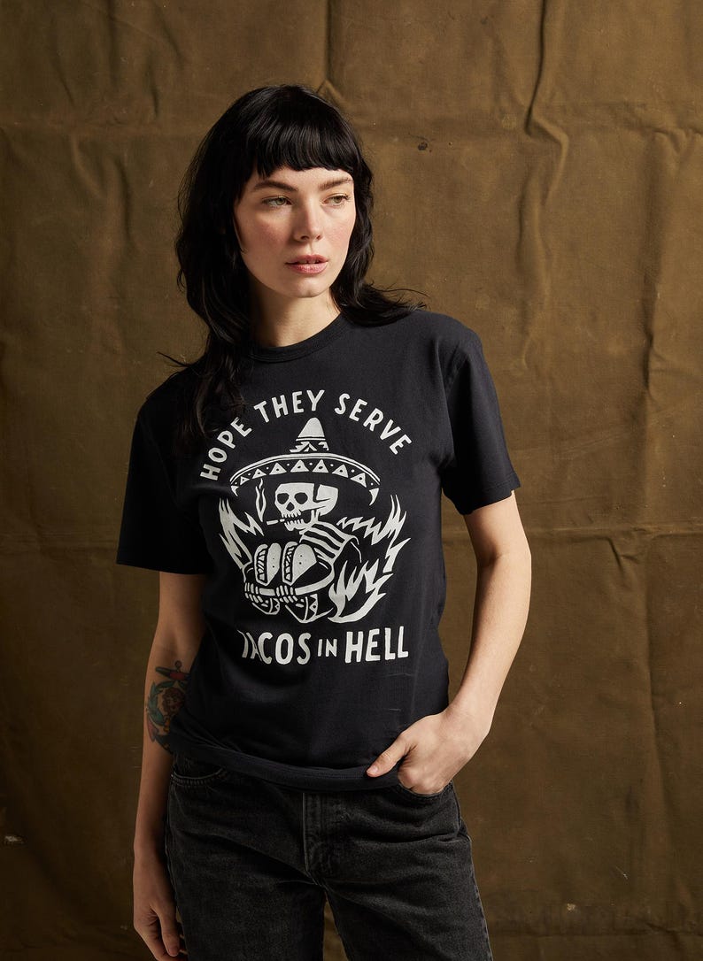 Peut inclure: T-shirt noir avec un graphique blanc d'un squelette portant un sombrero et tenant des tacos. Le texte "Hope they serve tacos in hell" est imprim&eacute; sous le graphique.