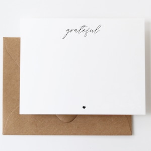 May include: A white card with the word "grateful" written in black cursive script. A small black heart is at the bottom of the card.