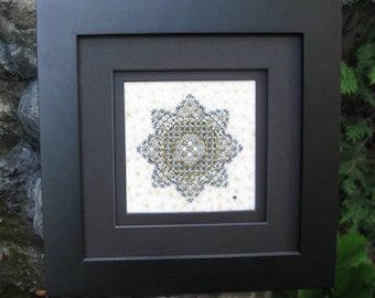 May include: A black framed picture with a white background and a black and gold geometric design in the center. The text "Tanja Berlin" is at the bottom of the image.