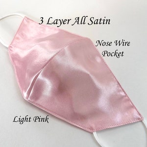 Puede incluir: M&aacute;scara facial de sat&eacute;n rosa claro con tres capas y un bolsillo para alambre nasal. La m&aacute;scara est&aacute; hecha de tela de sat&eacute;n suave y lisa.  "3 Layer All Satin" y "Nose Wire Pocket" est&aacute;n escritos en la m&aacute;scara.