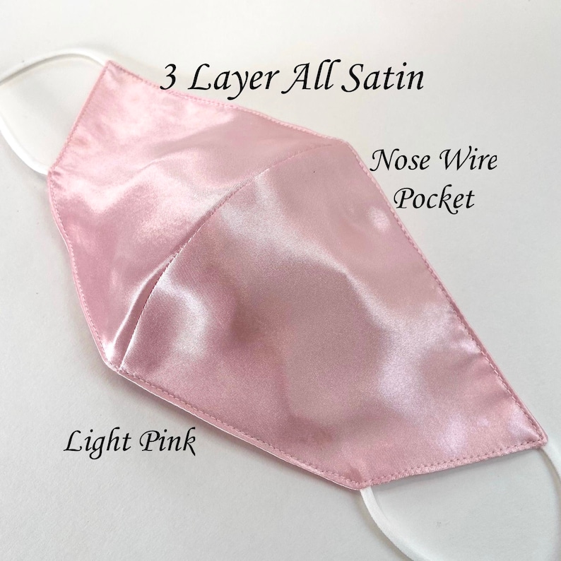 Puede incluir: M&aacute;scara facial de sat&eacute;n rosa claro con tres capas y un bolsillo para alambre nasal. La m&aacute;scara est&aacute; hecha de tela de sat&eacute;n suave y lisa.  "3 Layer All Satin" y "Nose Wire Pocket" est&aacute;n escritos en la m&aacute;scara.