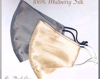 May include: Two 100% mulberry silk face masks, one dark grey and one gold.  The masks have white elastic ear loops.