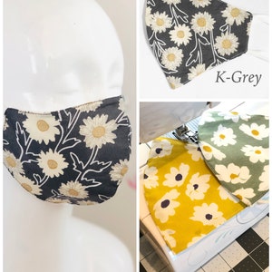 May include: Face masks with daisy floral patterns in gray, yellow, and green. The masks are shown on a mannequin head and separately. The masks have white elastic ear loops. The text "K-Grey", "K-Yellow", and "K-green" are visible.