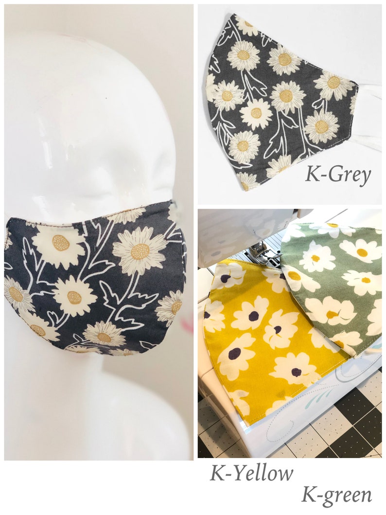 May include: Face masks with daisy floral patterns in gray, yellow, and green. The masks are shown on a mannequin head and separately. The masks have white elastic ear loops. The text "K-Grey", "K-Yellow", and "K-green" are visible.