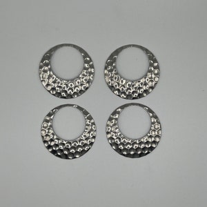 May include: Four silver metal rings with a textured, honeycomb-like design. The rings are all the same size and shape.