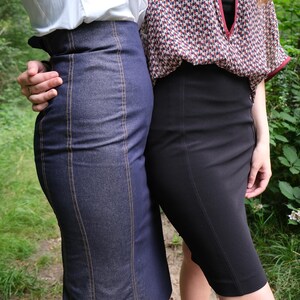 May include: Two women wearing skirts. One woman is wearing a white shirt and a denim skirt with vertical stitching. The other woman is wearing a patterned blouse and a black skirt.