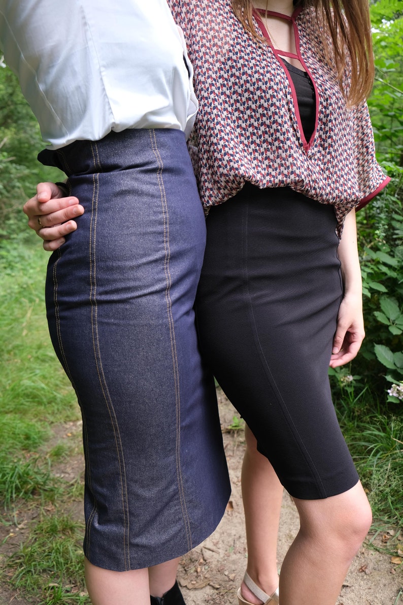 May include: Two women wearing skirts. One woman is wearing a white shirt and a denim skirt with vertical stitching. The other woman is wearing a patterned blouse and a black skirt.