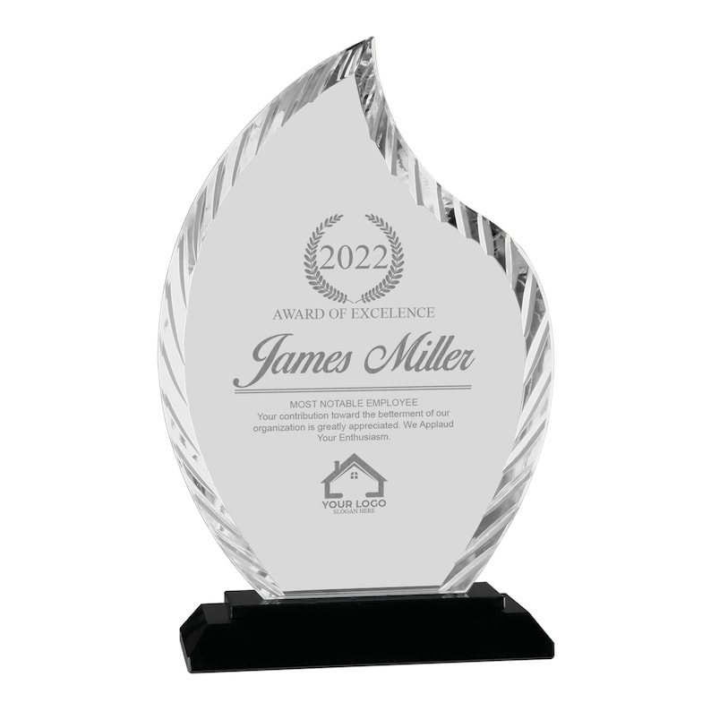 May include: A clear glass award in the shape of a flame with a black base. The award has an inscription that reads "2022 Award of Excellence James Miller Most Notable Employee Your contribution toward the betterment of our organization is greatly appreciated. We Applaud Your Enthusiasm. YOUR LOGO SLOGAN HERE"