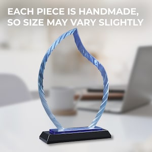 May include: A blue glass award with a flame-shaped design. The award has a black base and a blue accent.