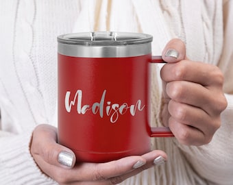 May include: A red insulated travel mug with a silver lid and handle. The name "Madison" is written in a cursive font on the side of the mug. The mug is designed to keep beverages hot or cold.