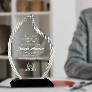 May include: A clear glass award in the shape of a flame with the text "LIFETIME ACHIEVEMENT AWARD" and "Jennifer Hamilton" engraved on it. The award also includes the text "MOST NOTABLE EMPLOYEE" and "YOUR LOGO".