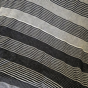 Może przedstawiać: Czarno-biała, prążkowana narzuta z fakturowanym wzorem dzianiny. Narzuta wykonana jest z miękkiego, przytulnego materiału i idealnie nadaje się do dodania odrobiny stylu do każdego pomieszczenia.