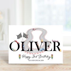 Op de afbeelding: Een witte verjaardagskaart met een raceautothema. De naam "OLIVER" staat prominent in beeld, met raceauto's en een racecircuitontwerp. De tekst "Happy 3rd Birthday" en "To a very special son" is ook aanwezig.