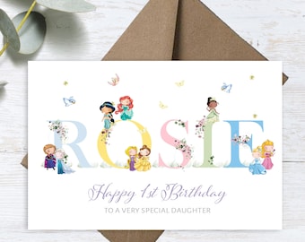 Puede incluir: Una tarjeta blanca con una ilustración colorida de princesas Disney que deletrean el nombre "ROSIE" con flores y mariposas. El texto "Feliz 1er cumpleaños a una hija muy especial" está impreso debajo del nombre.