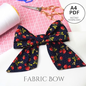 Puede incluir: Un lazo de tela azul marino con un patrón de lunares blancos y un estampado de fresas rojas. El lazo está atado y listo para ser usado como un lazo para el cabello o un elemento decorativo.