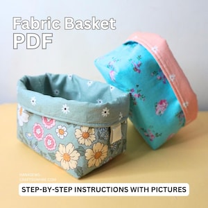 May include: Two fabric baskets with floral patterns. The basket on the left is green with yellow, pink, and white flowers. The basket on the right is blue with white and pink flowers. The text "Fabric Basket PDF" is at the top of the image. The text "Step-by-step instructions with pictures" is at the bottom of the image.