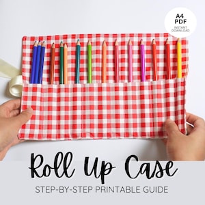 Op de afbeelding: Een rood-wit geruite oprolbare etui met een verscheidenheid aan kleurpotloden. De etui is gemaakt van stof en heeft een lint. De tekst "Roll Up Case" en "STEP-BY-STEP PRINTABLE GUIDE" worden onderaan de afbeelding weergegeven.