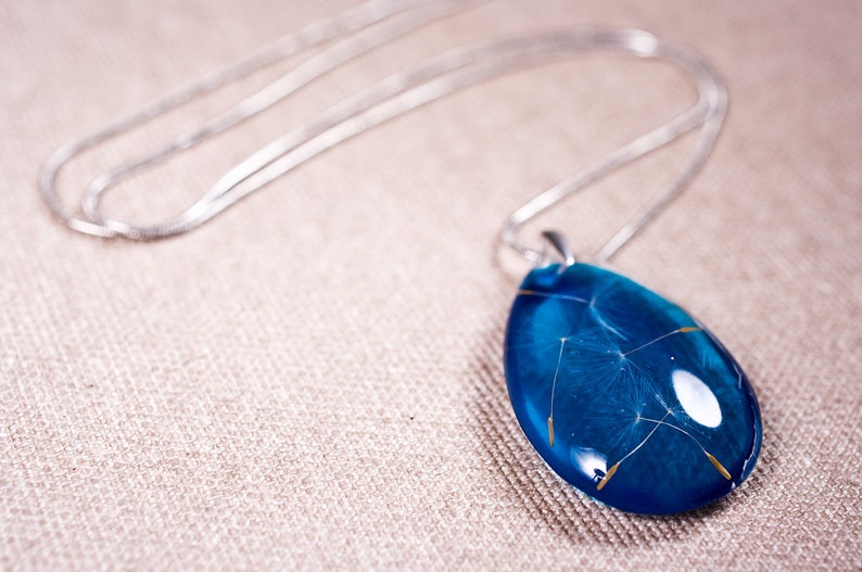 Delicate blue resin pendant with real dandelion seeds: