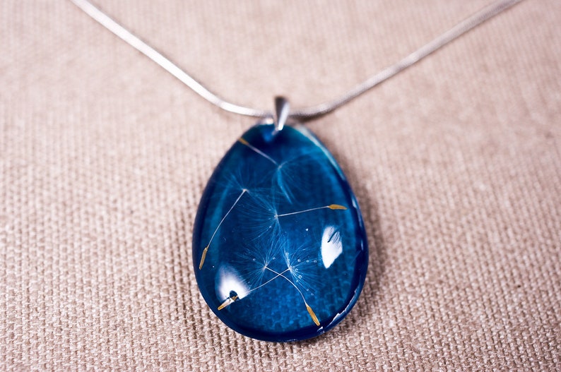 Delicate blue resin pendant with real dandelion seeds: