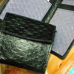 May include: A black leather wallet with a textured, scaly pattern. The wallet is folded closed and has a flap.