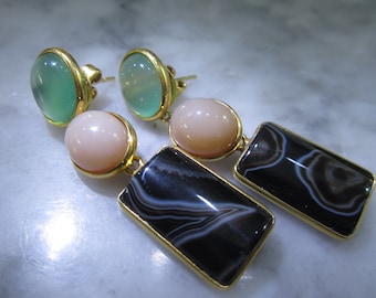 May include: A pair of gold earrings with three stones each. The top stone is green, the middle stone is pink, and the bottom stone is black with white swirls.