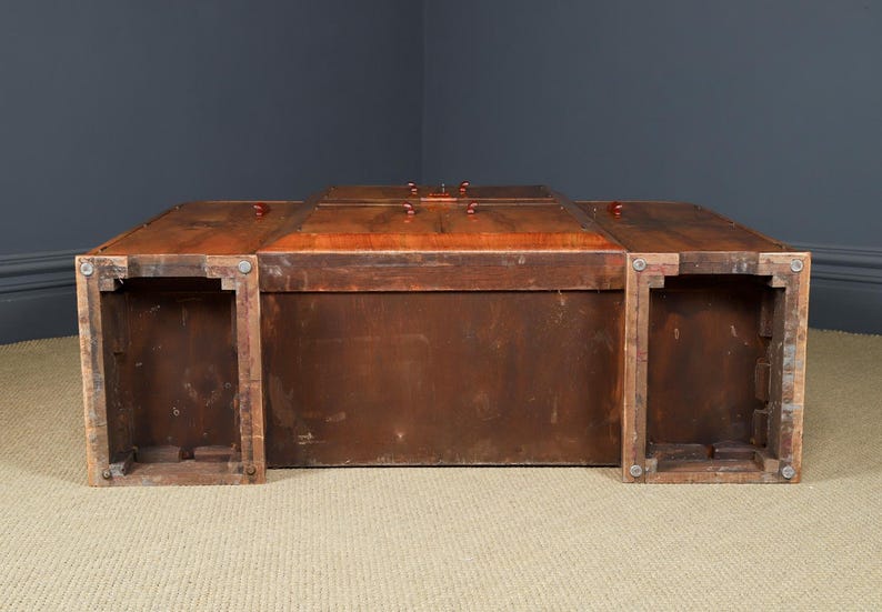 May include: A large, rectangular wooden trunk with a rich, reddish-brown finish. The trunk features a hinged lid with several small, round knobs and is supported by four sturdy legs. The overall design suggests a vintage or antique style.