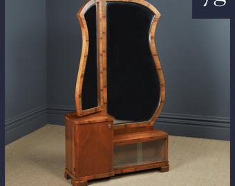 May include: A vintage wooden vanity with a three-panel mirror. The mirror has a unique, curved shape and is framed in wood. The vanity has a single drawer and a shelf with glass doors.