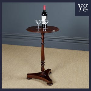 May include: A dark brown, round side table with a single pedestal base. A bottle of red wine and two stemmed glasses sit on the table. The table is approximately 28 inches tall.