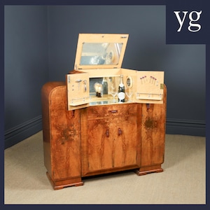May include: A vintage wooden bar cabinet with a mirrored interior and a fold-out design. The cabinet features a rich, warm wood grain finish and includes a bottle of champagne, glassware, and bar tools. The cabinet is a stylish piece of furniture.