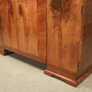 May include: A wooden cabinet with a warm, reddish-brown finish. The cabinet has a rectangular shape with two doors and decorative handles. The wood grain is visible, adding to the cabinet's natural aesthetic. The cabinet sits on a low base.