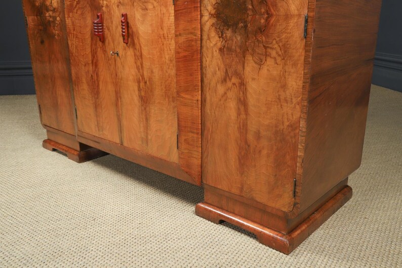 May include: A wooden cabinet with a warm, reddish-brown finish. The cabinet has a rectangular shape with two doors and decorative handles. The wood grain is visible, adding to the cabinet's natural aesthetic. The cabinet sits on a low base.