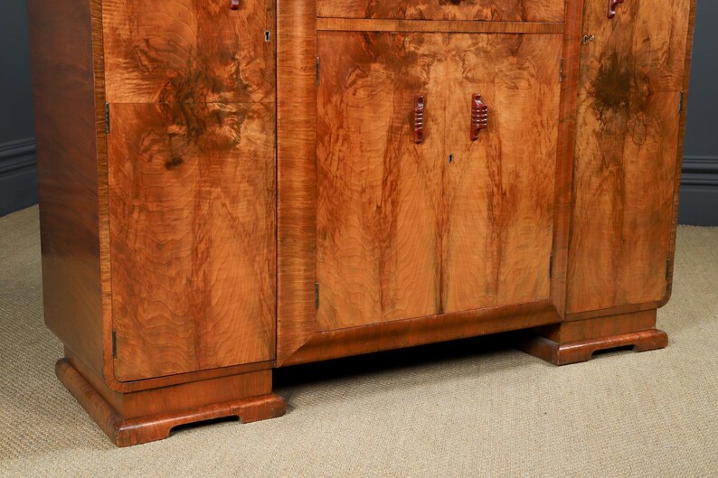May include: A vintage wooden cabinet with a warm, reddish-brown finish. The cabinet features a symmetrical design with doors, drawers, and decorative handles. The wood grain is prominent, adding to its classic appeal. The cabinet sits on a sturdy base.