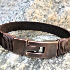 May include: Brown leather bracelet with a copper clasp and the inscription "I love you Officer Charles".
