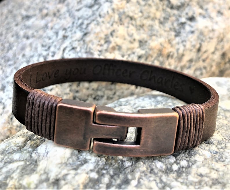 May include: Brown leather bracelet with a copper clasp and the inscription "I love you Officer Charles".
