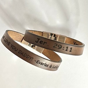 May include: Two brown leather bracelets with engraved text. One bracelet reads "Jer. 29:11" and the other reads "We love you daddy! - Everlee & Laikyn".