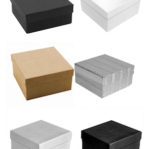 May include: A collection of square gift boxes in various colors and textures. The boxes include black, white, kraft paper, silver, and patterned white and black. Each box has a matching lid.