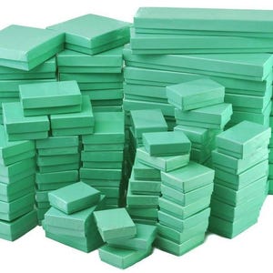 May include: A collection of various sized, rectangular, light green gift boxes stacked in multiple piles. The boxes are made of a smooth material and are all the same color. The boxes are empty and ready to be filled with gifts.