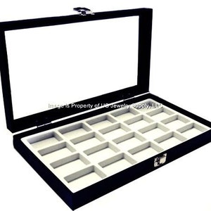 May include: Black velvet jewelry display box with a clear glass lid and 12 compartments. The box is open and the compartments are lined with white felt.
