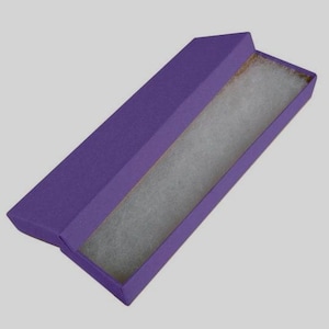 May include: A rectangular purple cardboard jewelry box with a hinged lid. The interior of the box is lined with a soft, white, textured cotton-like insert designed to hold small items securely in place. The exterior has a matte finish.