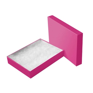 May include: A pink gift box with a white padded interior. The box is open and the lid is lying next to it.