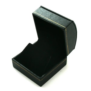 May include: A black ring box with a gold trim. The box is open and the inside is lined with black velvet.