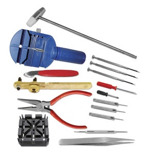 May include: A collection of watch repair tools, including a blue watch case opener, screwdrivers, pliers with red handles, and a silver T-bar tool. The tools are arranged on a white background.