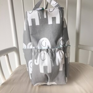 May include: A gray fabric storage bin with white elephant designs. The bin has multiple pockets and a drawstring closure.
