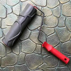 May include: A gray textured roller with a red handle. The roller is designed to create a stone pattern on walls or floors.