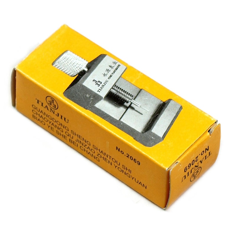 May include: A watch repair tool kit, featuring a silver metal watch hand remover and a yellow box with Chinese text and the brand name "TIANJIU". The box also has the number "No.2069" printed on it.