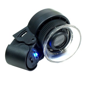 May include: A black, handheld magnifying glass with a clear, circular lens and a blue LED light. The device has a ridged focus adjustment ring and a pivoting arm. The lens is surrounded by a clear plastic shield.