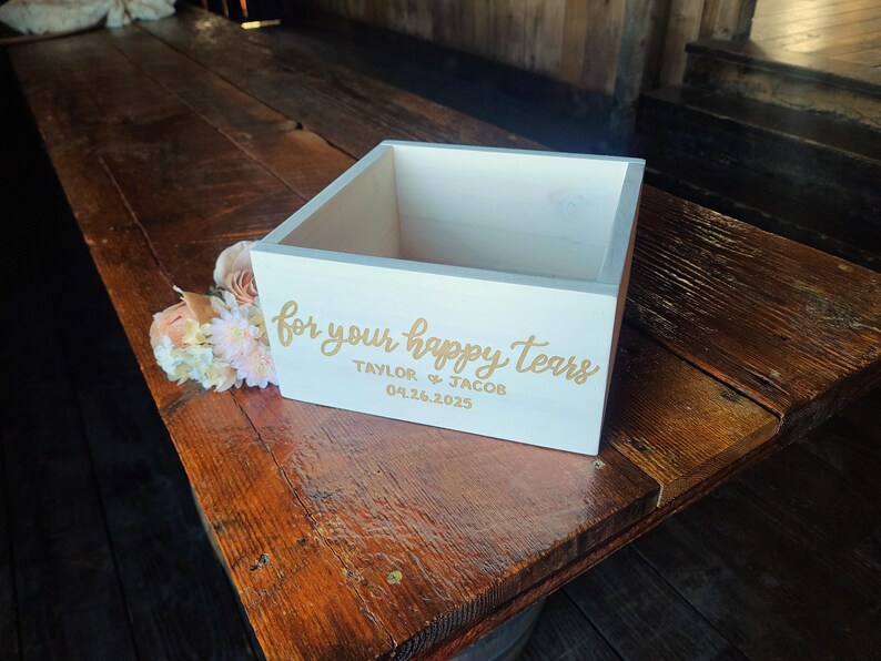 Pode incluir: Caixa de madeira branca com o texto "for your happy tears" em letras douradas. A caixa &eacute; personalizada com os nomes "Taylor & Jacob" e a data "04.26.2025".